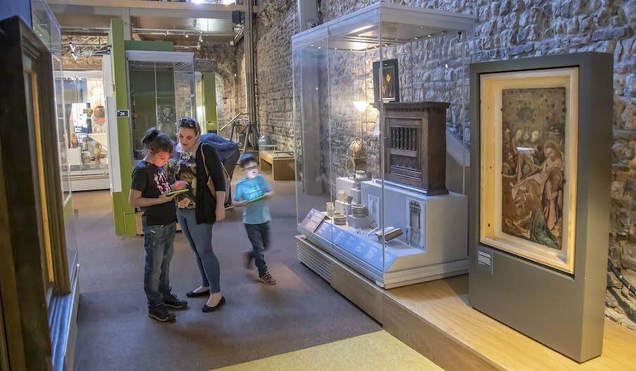 A family using a tablet to enjoy the displays at Colchester Castle Museum